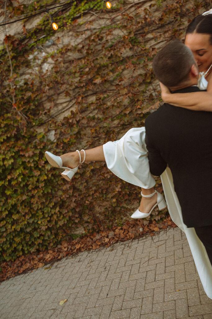 Groom lifting his bride in his arms during their Clarkston, Michigan wedding portraits. 