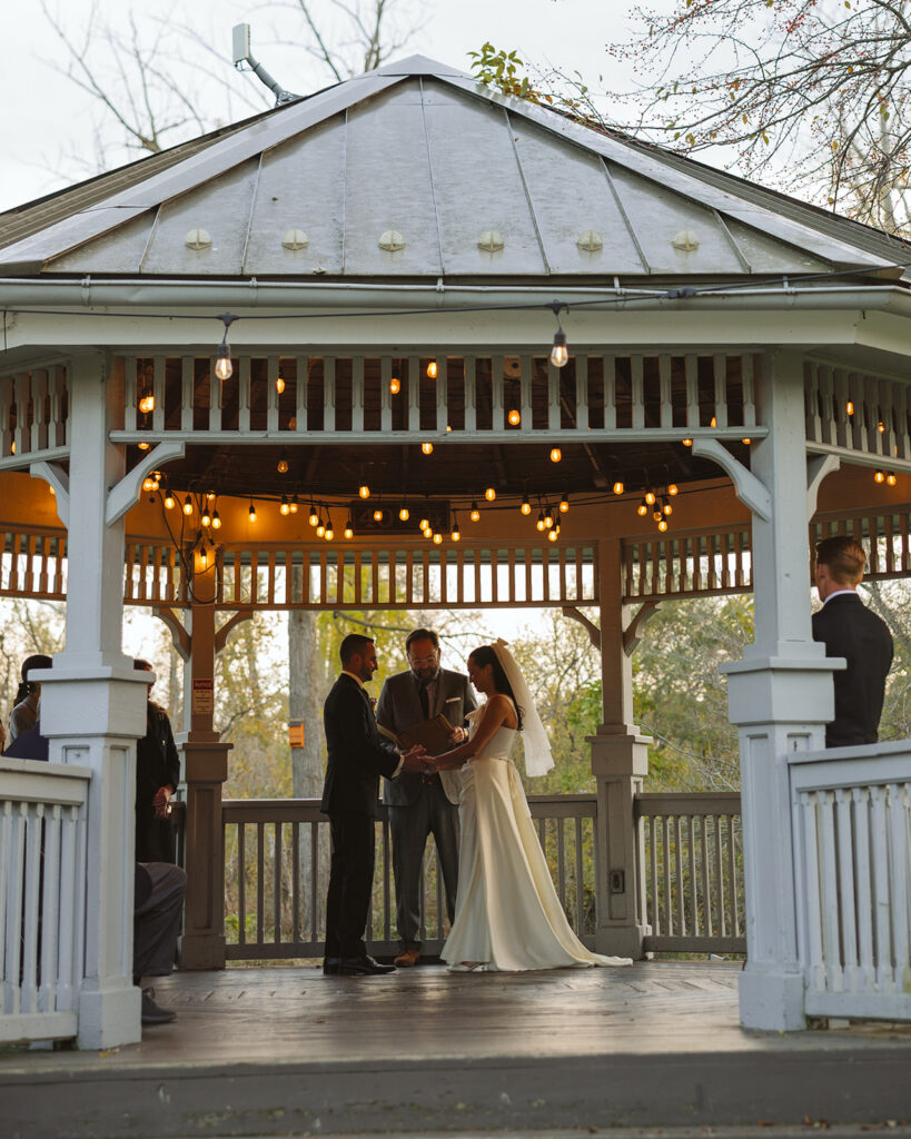 Bride and groom standing together during intimate outdoor ceremony at Depot Park in Clarkston Michigan.
