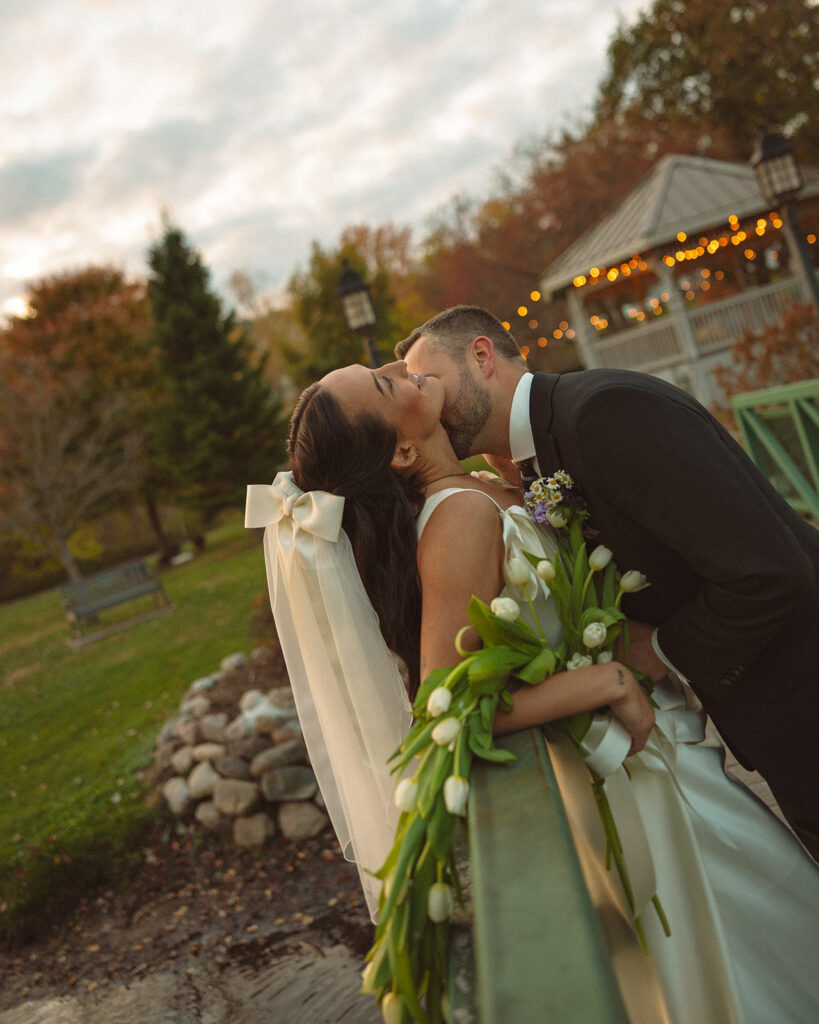 Groom kissing the brides neck during their Clarkston Michigan wedding portraits at the park.