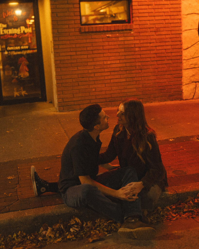Couple sitting on a sidewalk in front of The Evening Post Bar & Grill in Clare, Michigan.
