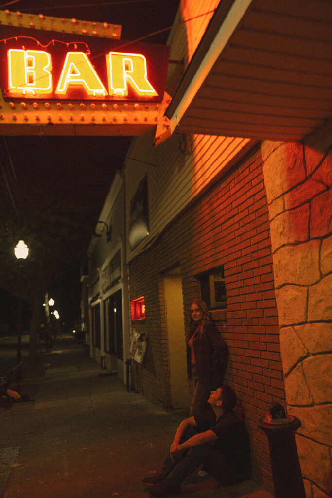 Couple leaning against a brick wall outside of The Evening Post Bar & Grill in Clare, Michigan.