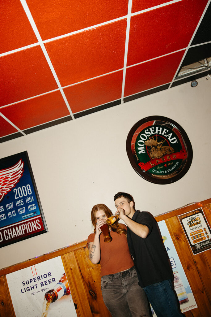 Flash photo of a couple drinking beers inside of The Evening Post Bar & Grill in Clare, Michigan.
