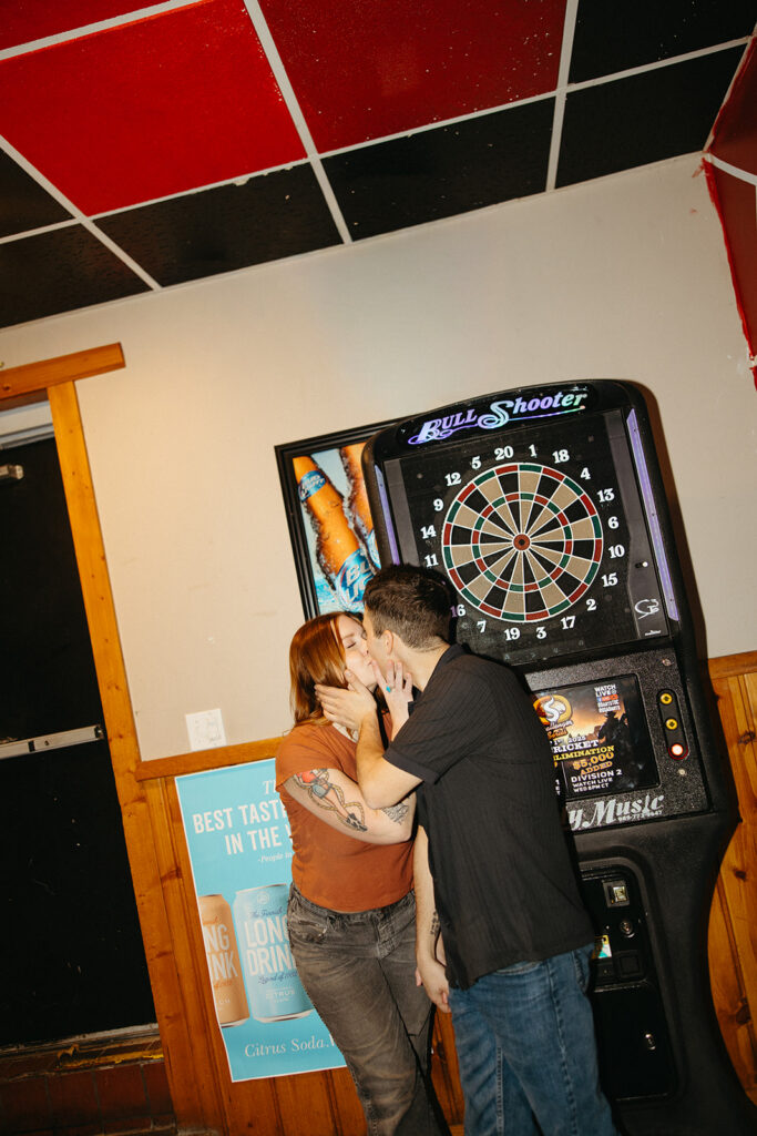 Couple kissing during their night-time dive-bar engagement photos in Michigan.