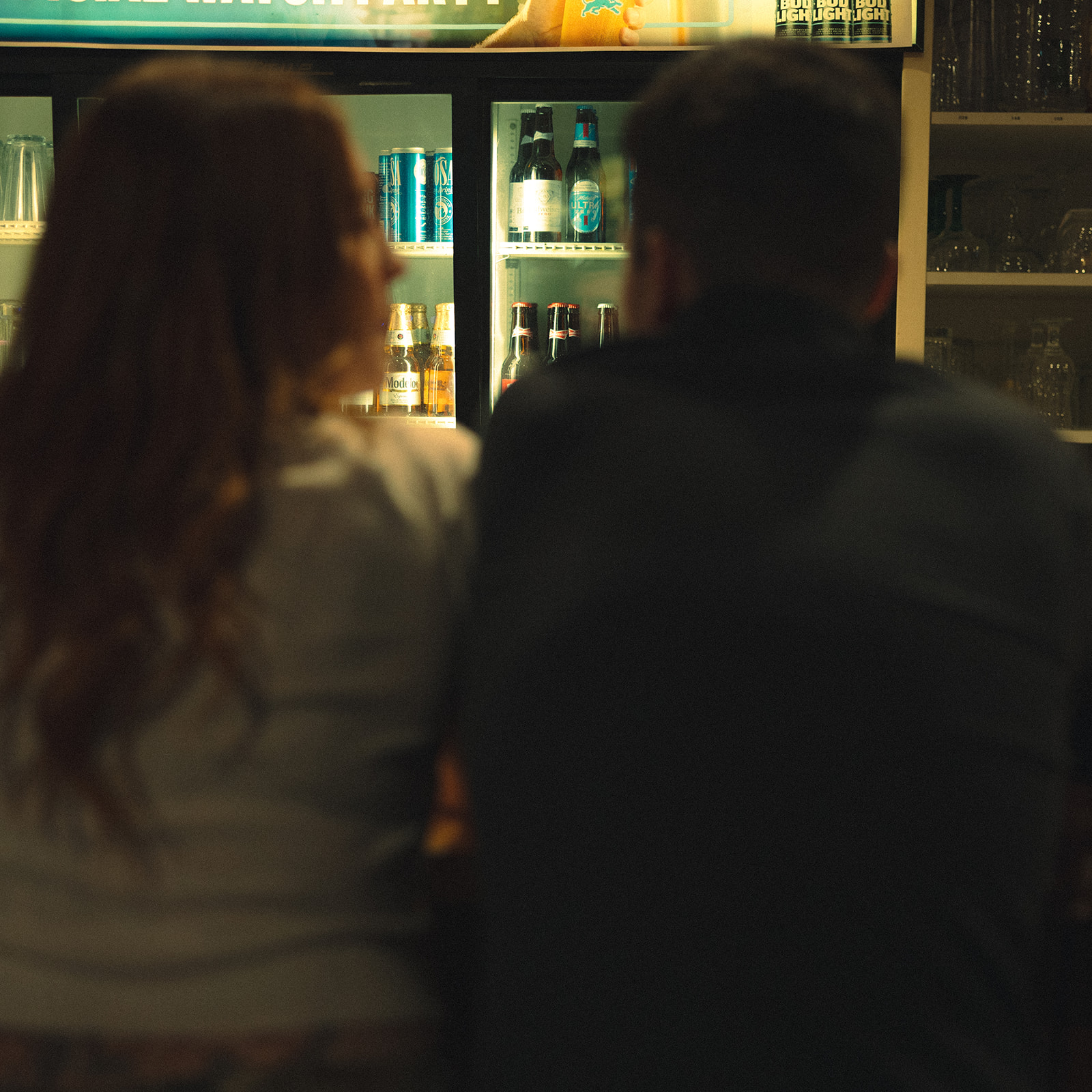 Couple sitting at the bar together during their dive-bar engagement photos in Michigan.