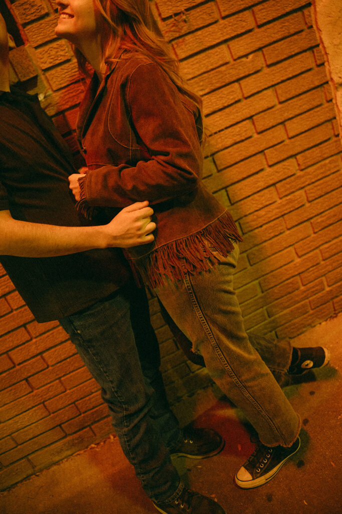 Close up shot of a couple holding on to another outside of a bar.