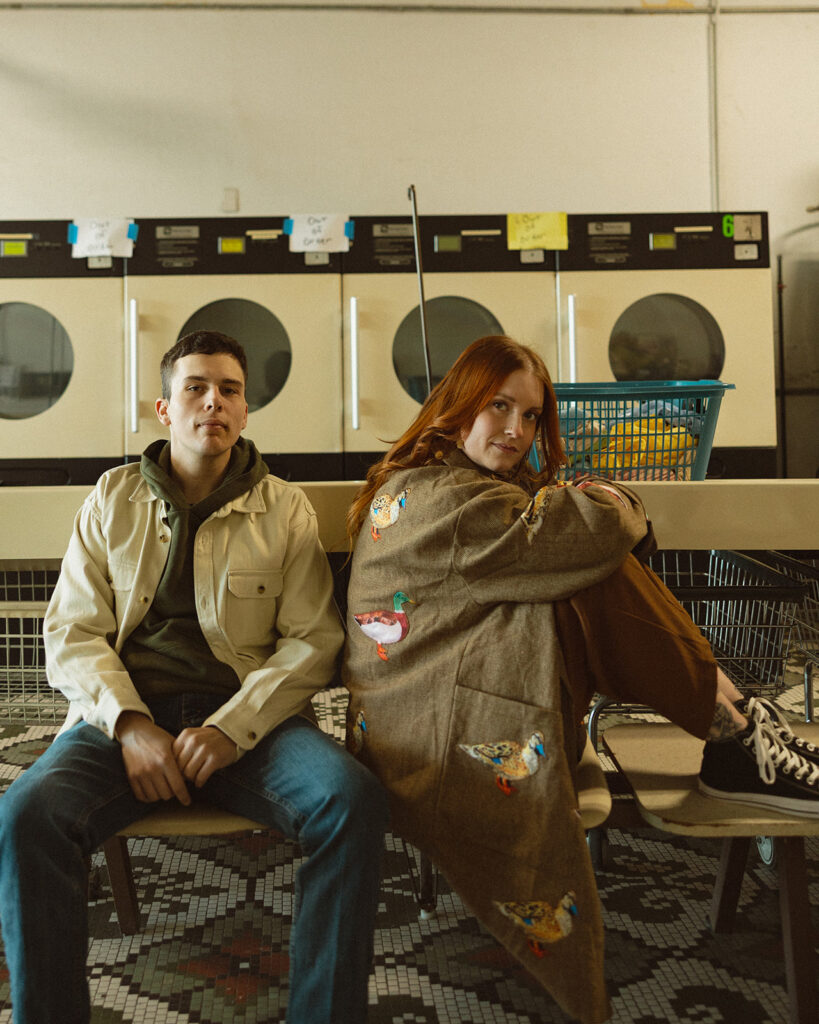 Couple posing inside of a vintage laundromat for their Michigan engagement photos.