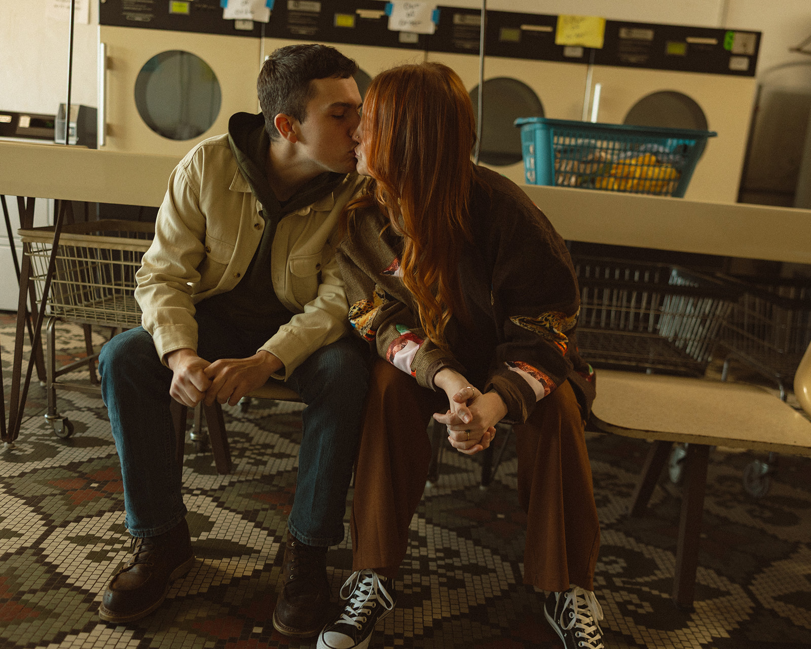 Couple sitting inside of a laundromat and kissing.