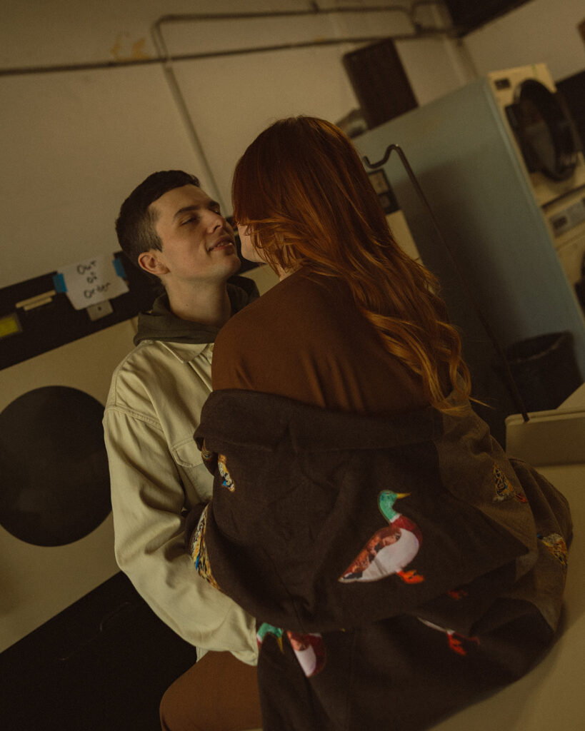 Couple sitting on a laundromat table for their Michigan engagement photos.