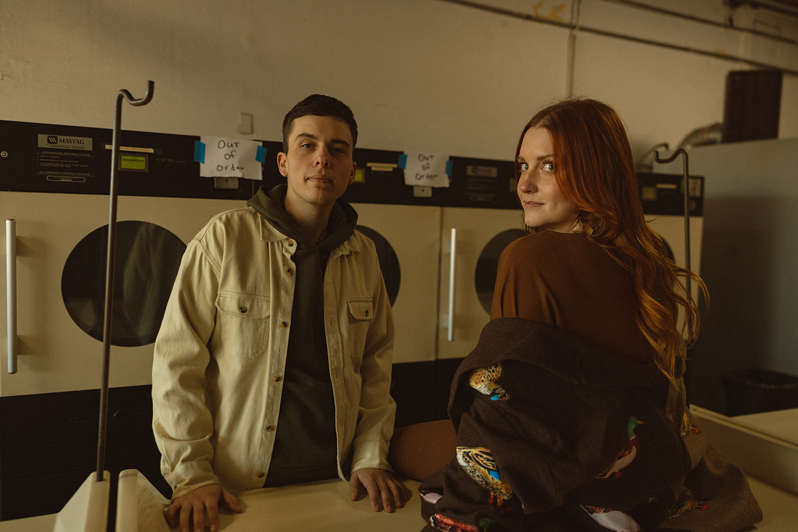 Couple looking back at the camera as they pose at a laundromat table.