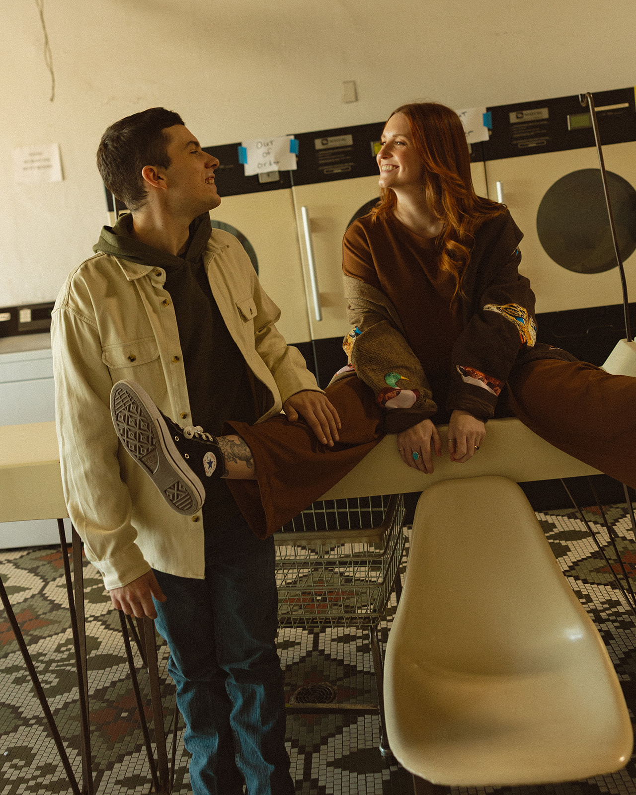 Couple being playful and smiling during their laundromat engagement photos in Michigan.