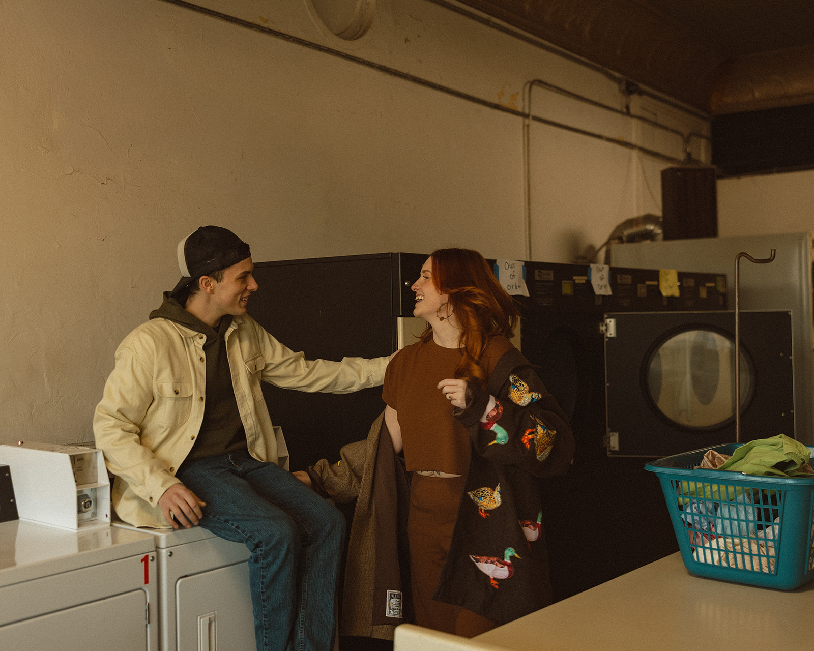 Candid photo of a couple laughing and being playful at their local laundromat. 
