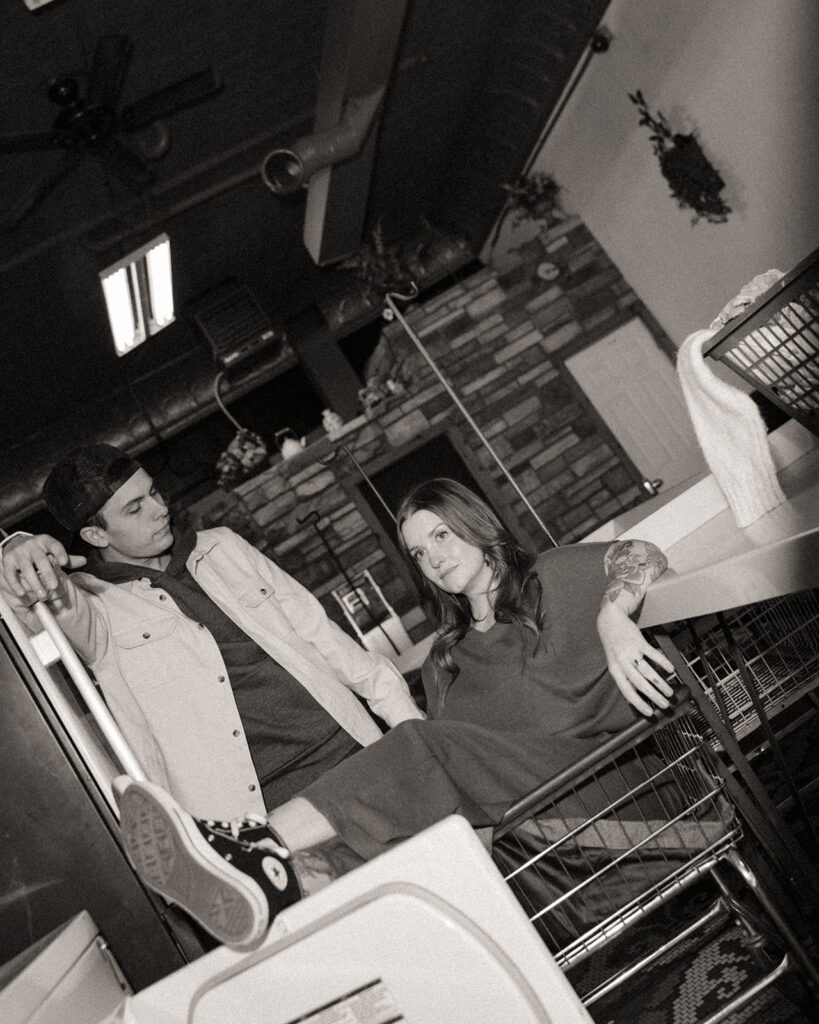 Black and white photo of a couple posing at a local laundromat. 
