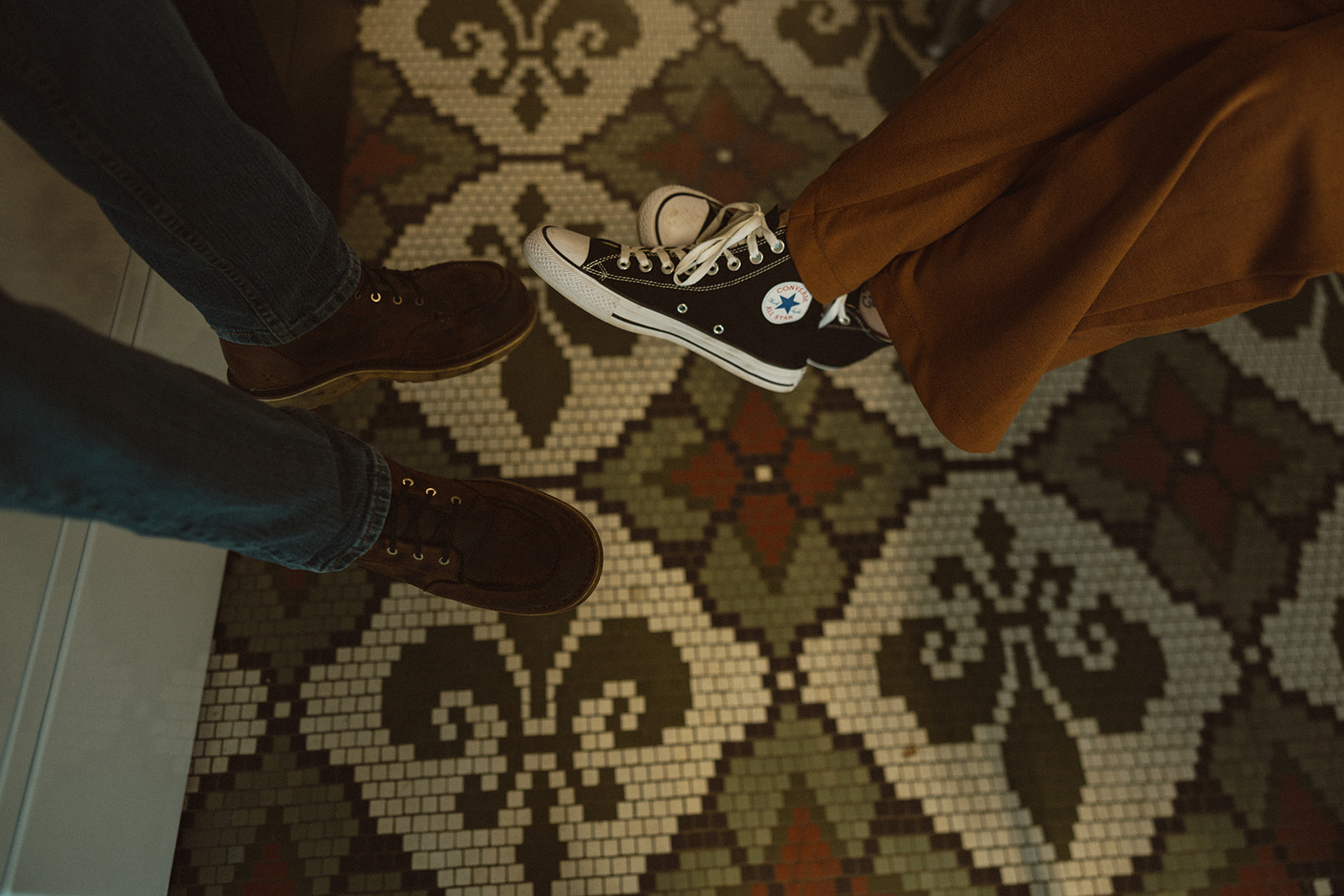 Close up shot of a couples feet as they sit in a laundromat with vintage flooring tile.