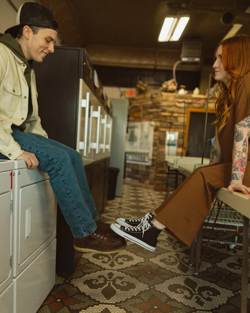 Couple touching feet as they pose at a Michigan laundromat.