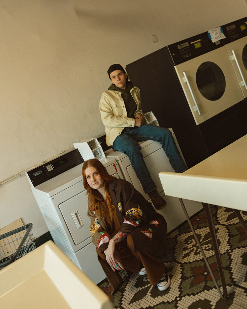 Couple posing in front of a laundromat for their Michigan engagement photos.