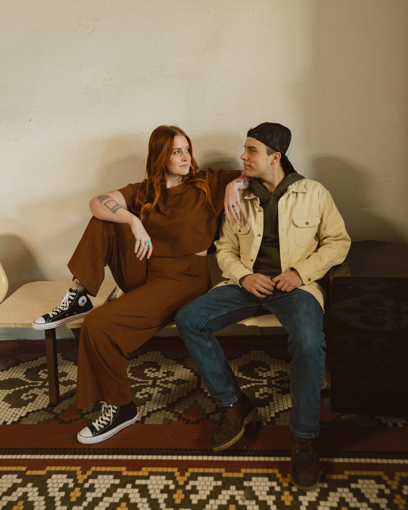 Couple sitting in seats at the laundromat for their artsy style engagement photos.