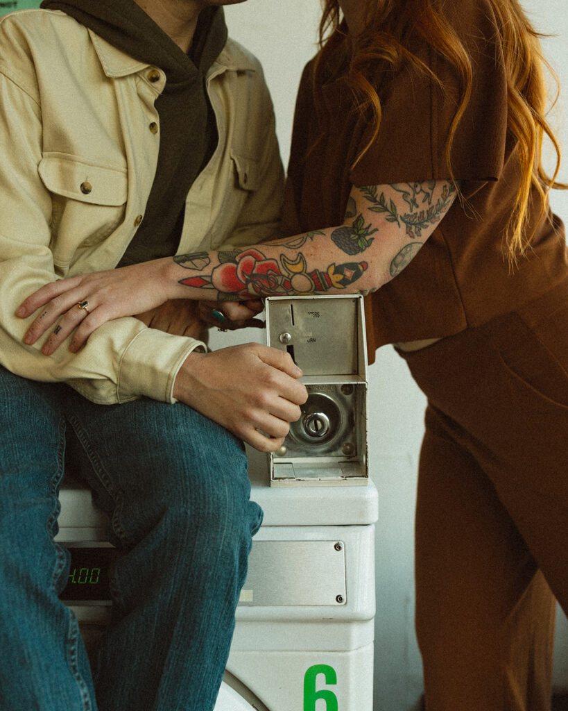Close up shot of a couple sitting at a washing machine at their local laundromat.