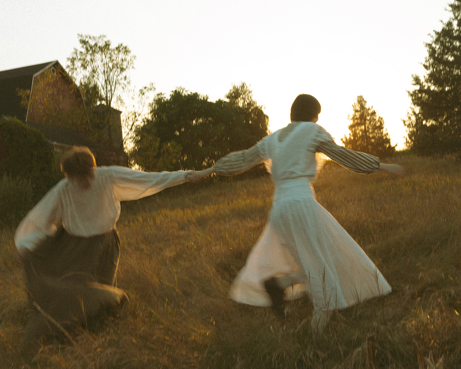 Motion-blurred portrait of a couple holding hands and running through a field at sunset for their unique Michigan engagement photos.