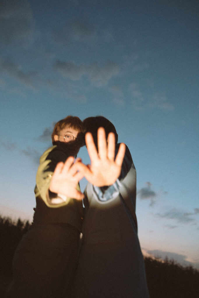 Playful blurred portrait of a couple reaching their hands toward the camera at dusk for their unique Michigan engagement photos.