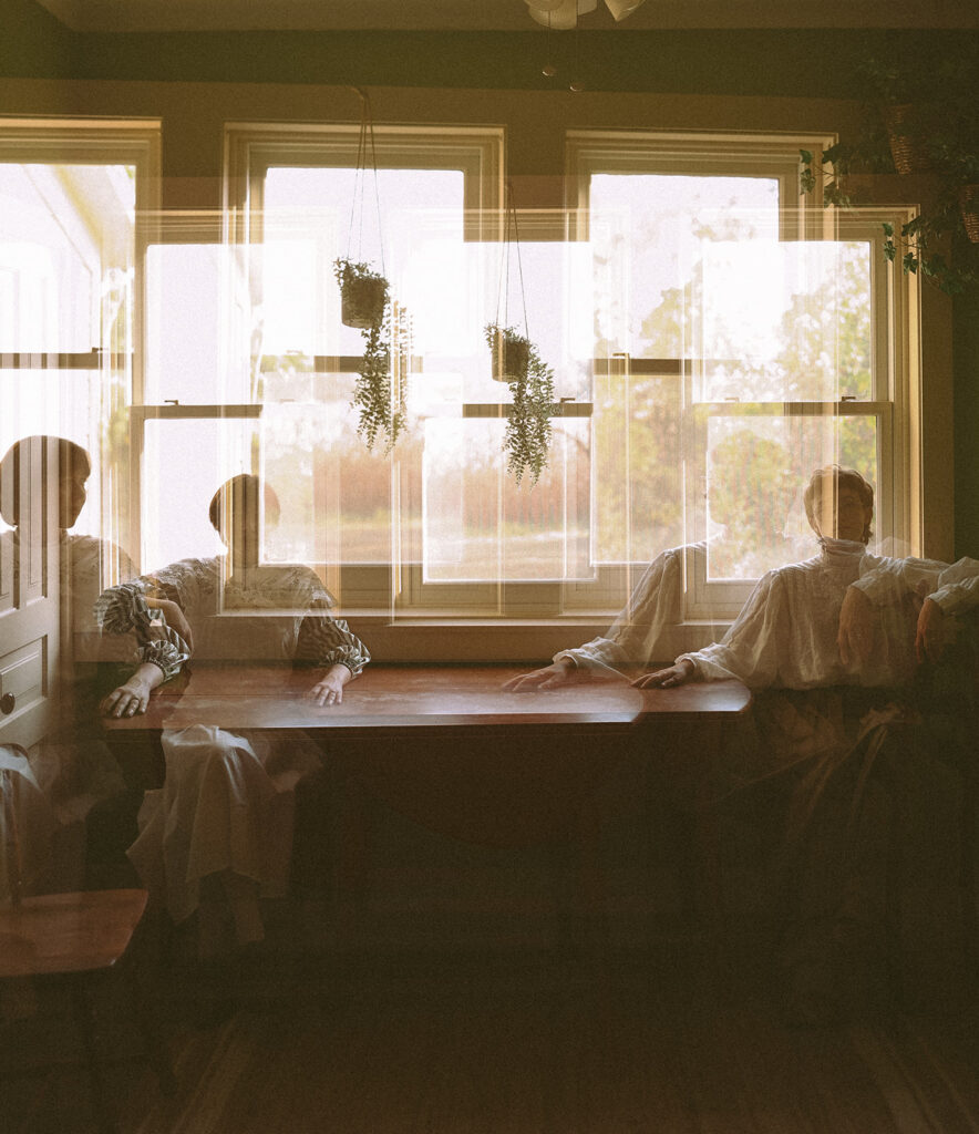 Double-exposure portrait of a couple seated by farmhouse windows during their Midwestern Gothic engagement session for their unique Michigan engagement photos.