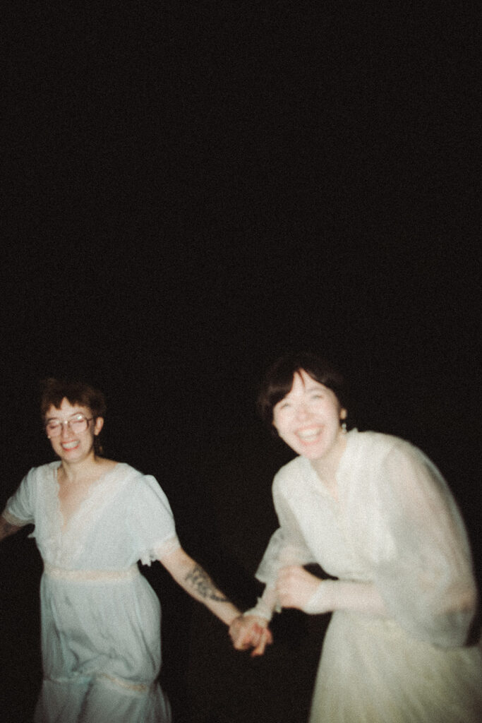 Couple holding hands and running toward the camera during their Midwestern Gothic engagement session.