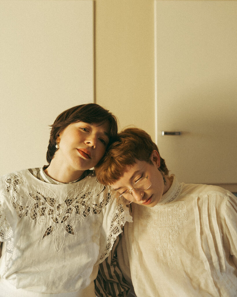 Couple resting their heads together while wearing lace and vintage-inspired clothing.