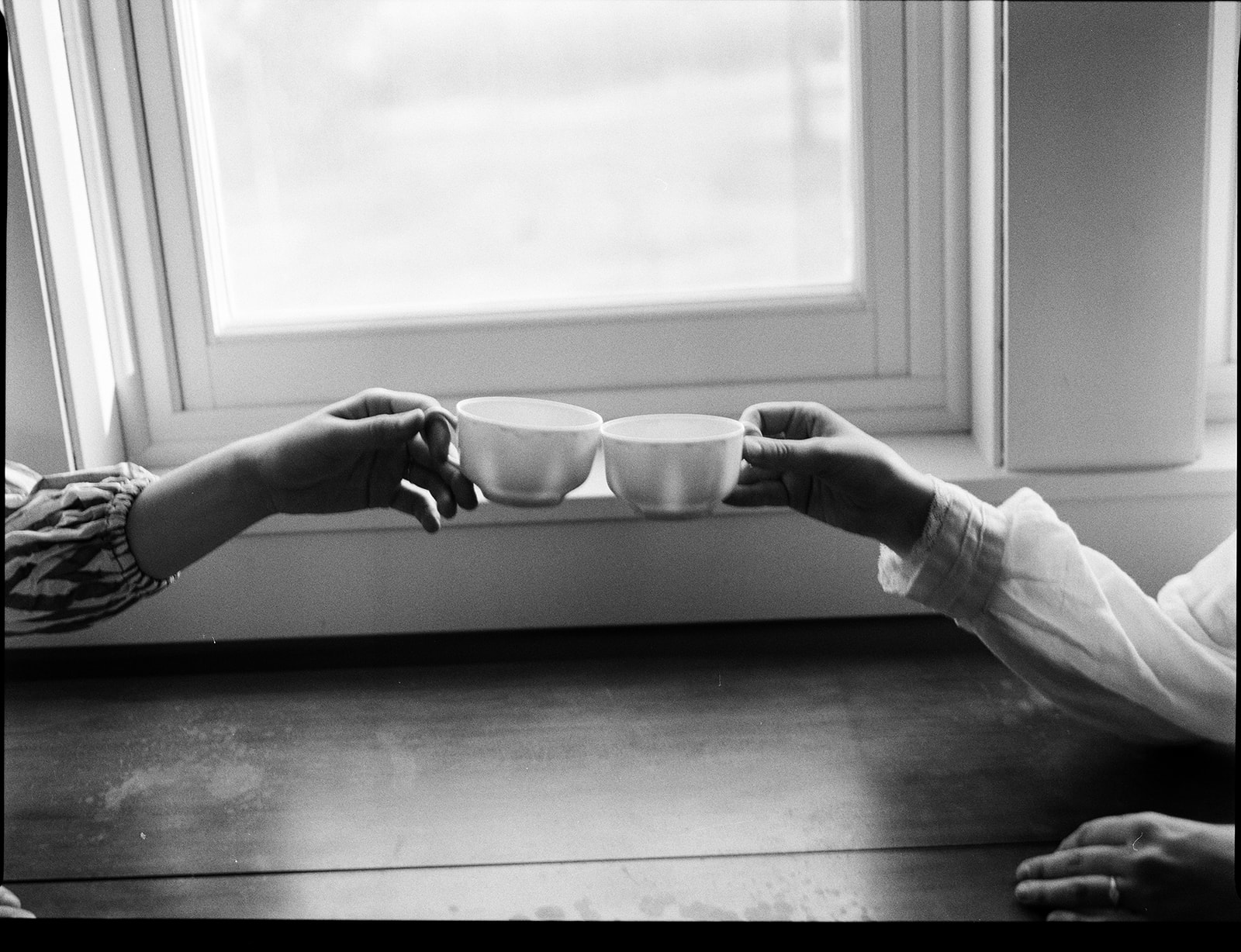 Black and white film photo of a couple clinking their tea glasses.
