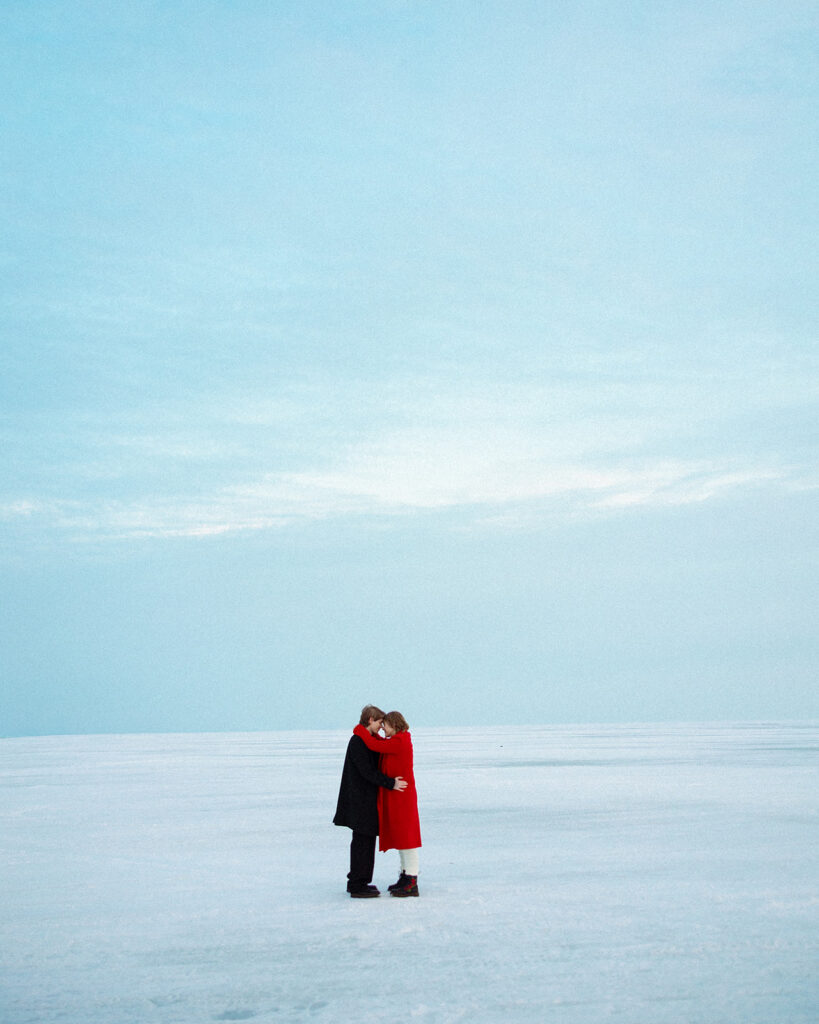 Couple standing together on the frozen lake during their Lake St. Clair Metropark engagement photos.