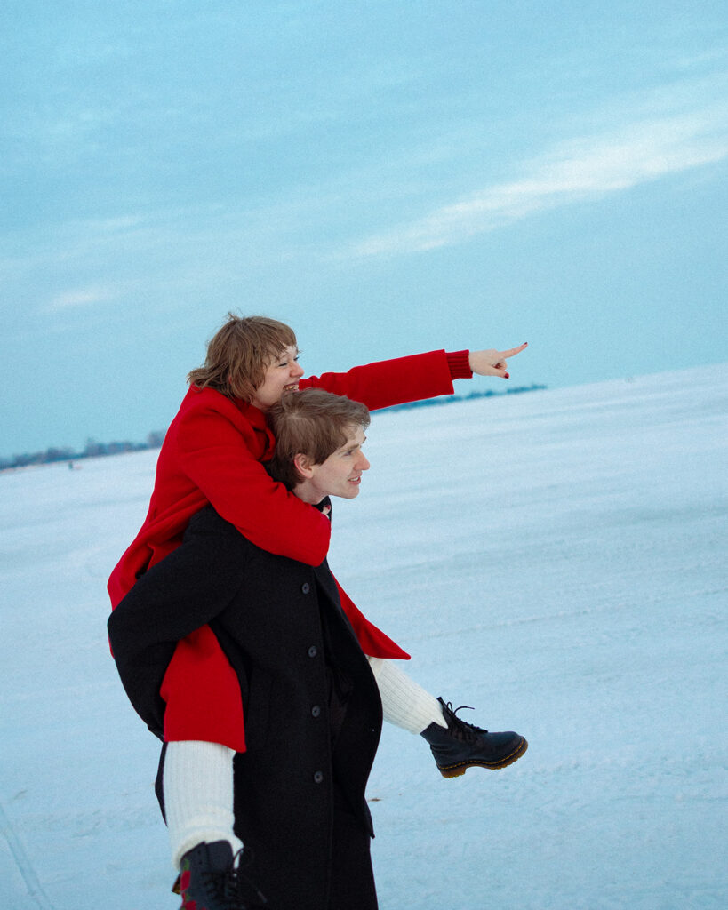 One partner giving the other a piggyback ride across the frozen lake.