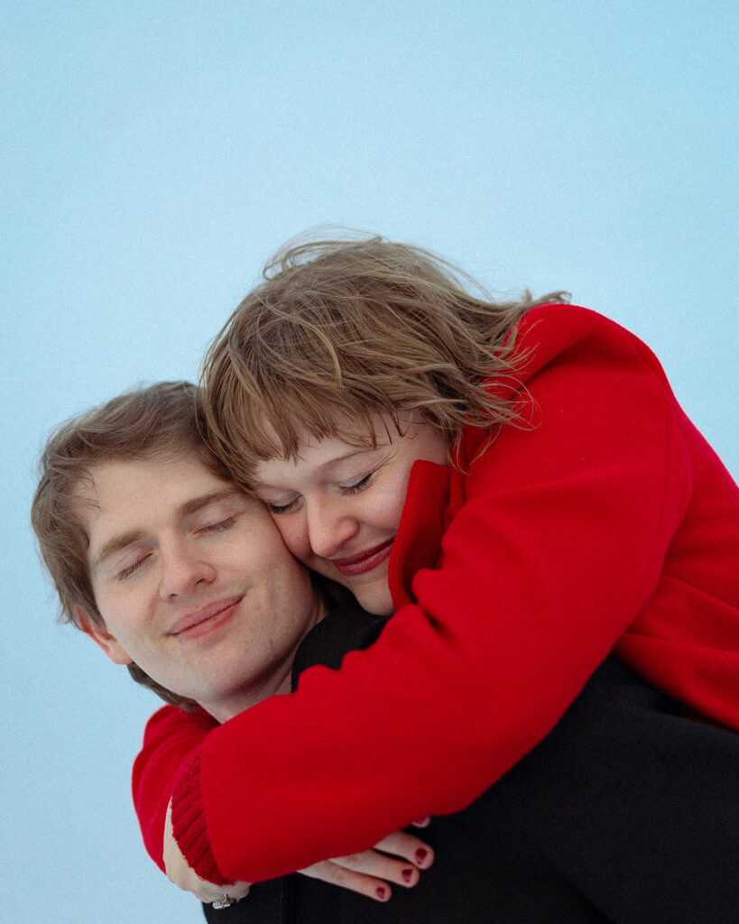 Man resting her head on her fiancés back as he gives her a piggy back ride.
