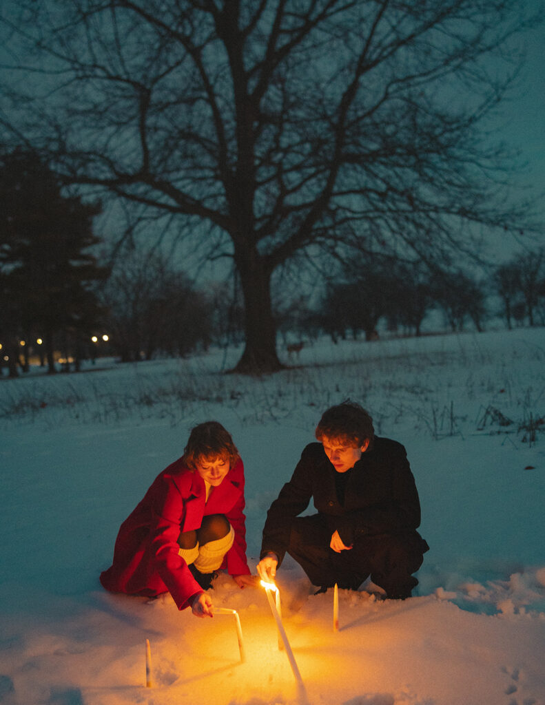 Couple lighting candles in the snow during blue hour at Lake St. Clair Metropark.