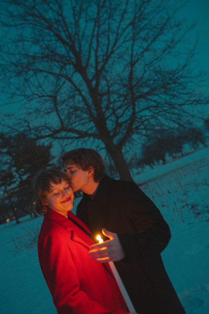 Man kissing his fiancé on the cheek during their outdoor Detroit winter engagement photos at Lake St. Clair Metropark.
