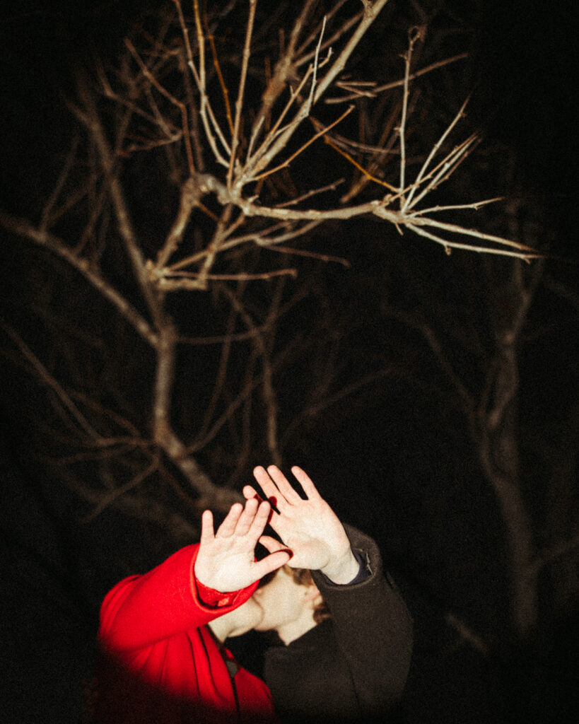 Couple holding their hands up to the camera flash during their nighttime Detroit winter engagement photos.