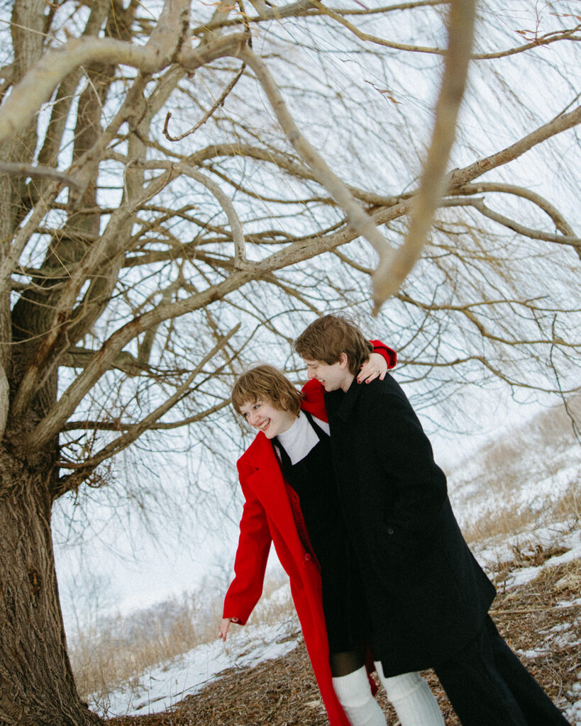 Couple laughing together beneath winter tree branches at Lake St. Clair Metropark.
