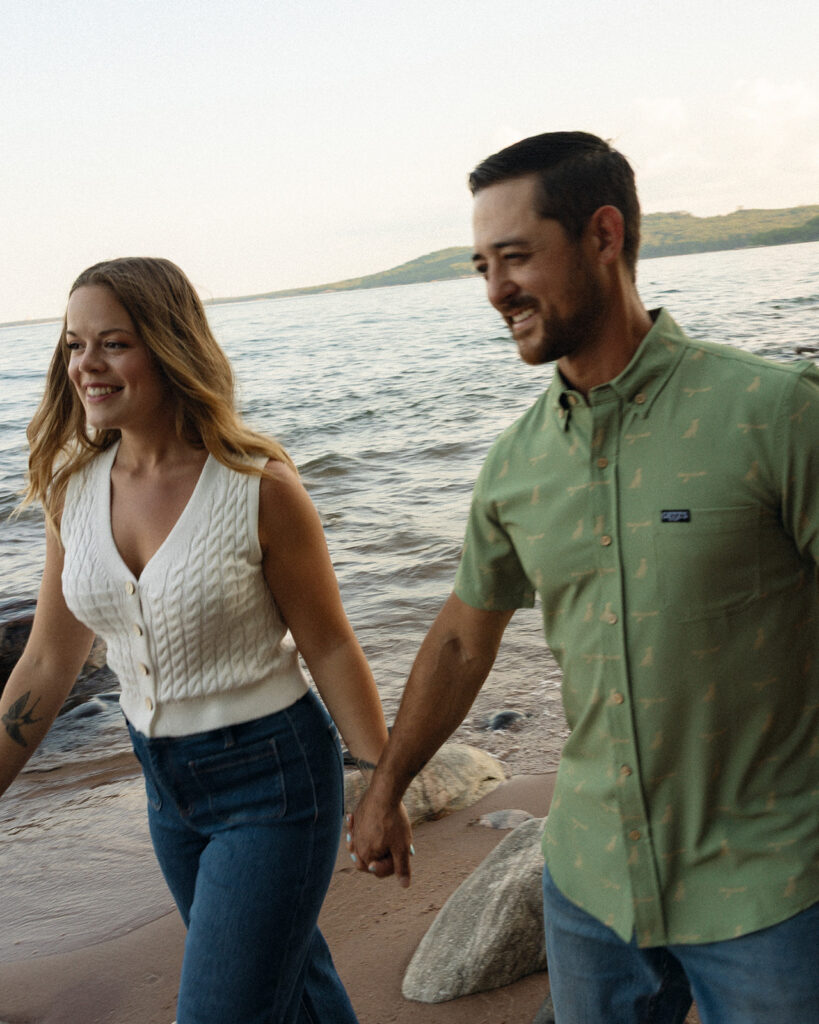 Couple holding hands while walking along the Lake Superior shoreline in Marquette, Michigan.