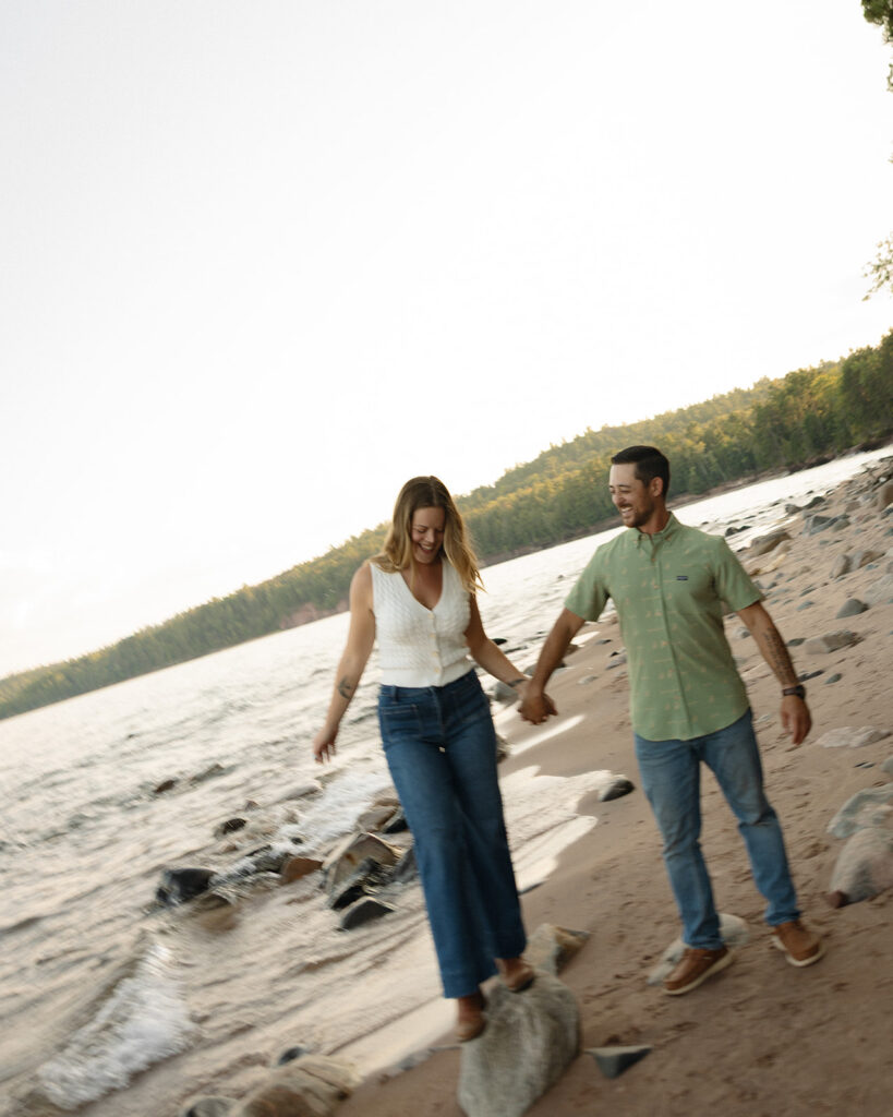 Couple holding hands while walking along the Lake Superior shoreline in Marquette, Michigan.