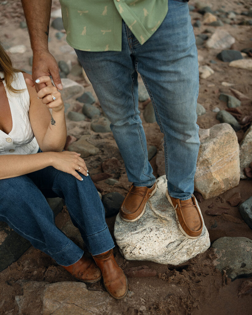 Close up photo of a couple holding hands on the shoreline.