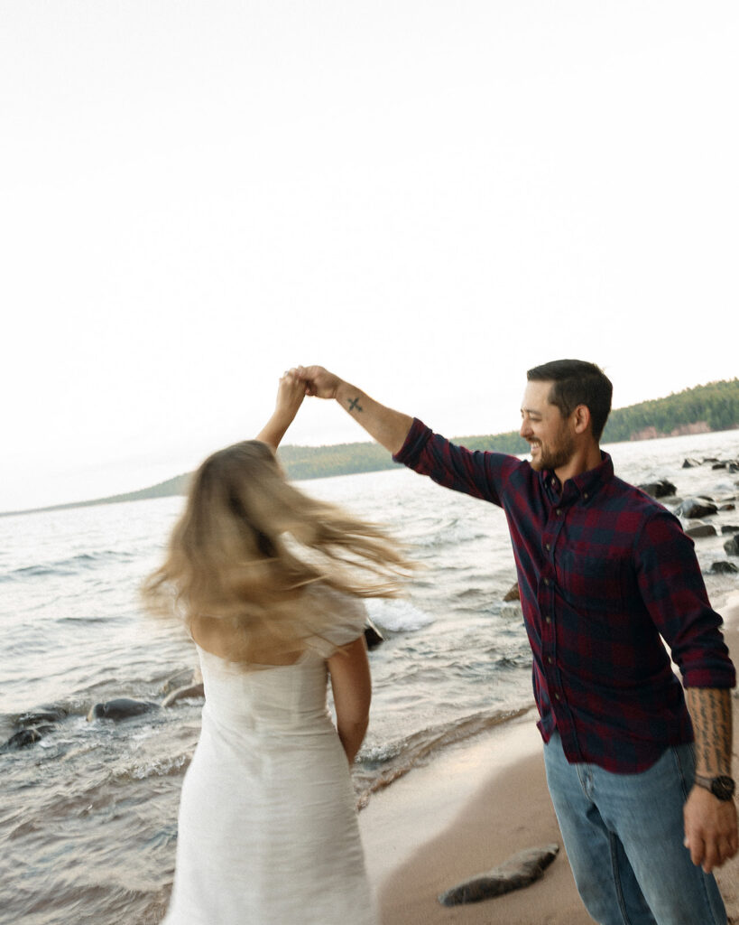 Couple dancing beside Lake Superior during their Little Presque Isle engagement photos.