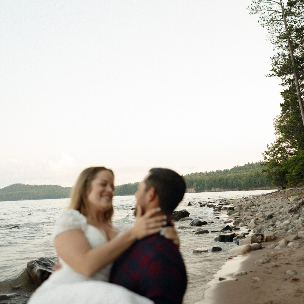 Man holding his fiancé up in his arms during their Marquette Michigan engagement photos.