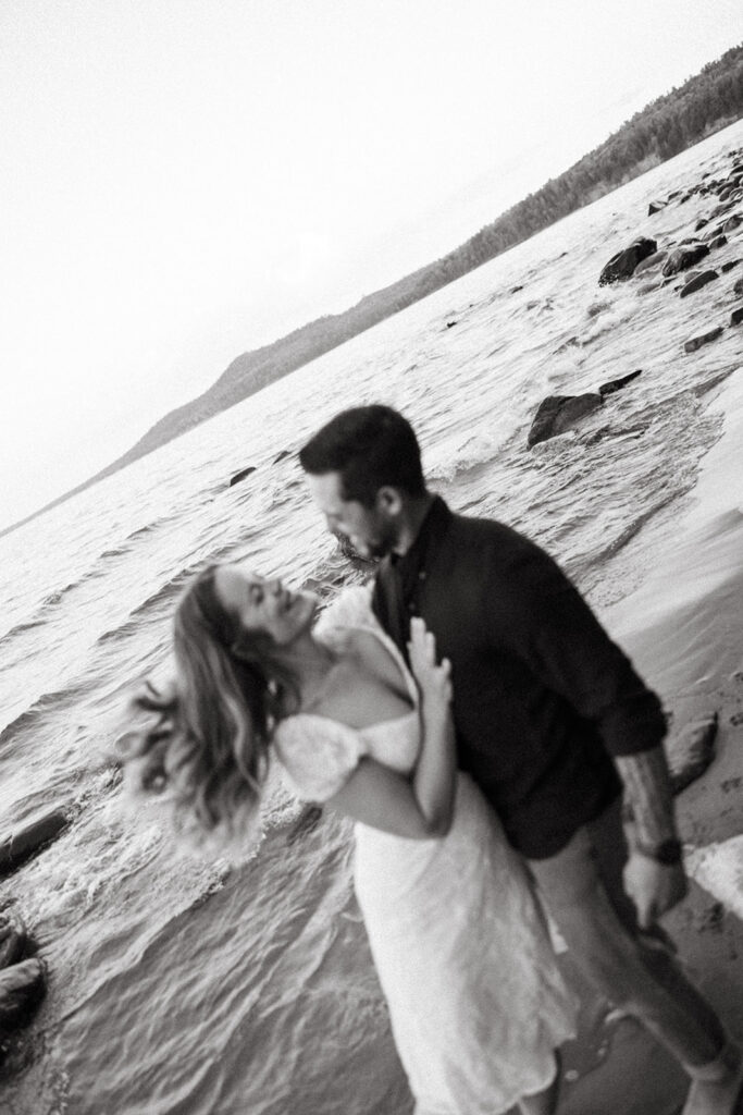 Blurred black-and-white photo of a couple leaning toward each other along the Lake Superior shoreline.