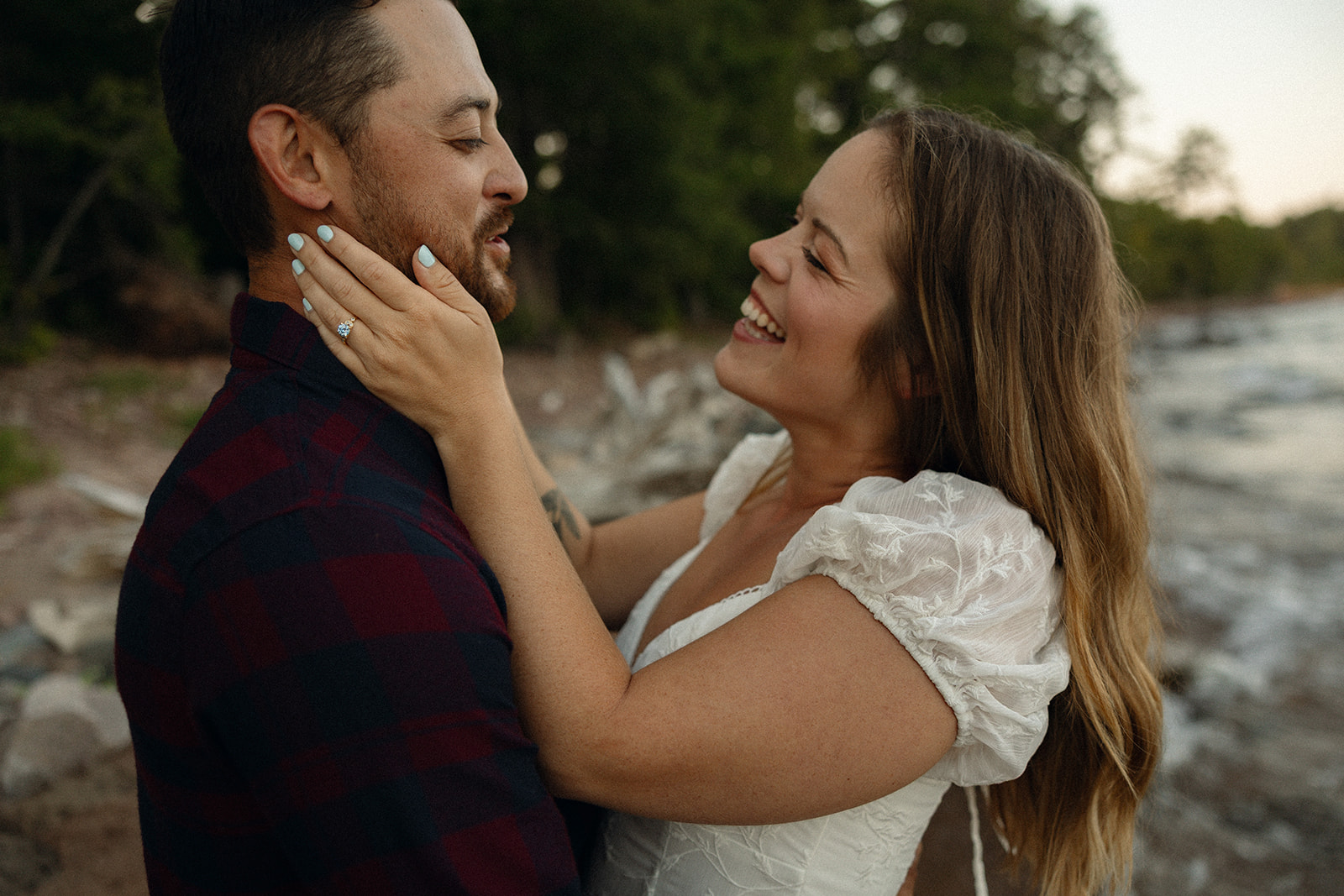Woman lovingly caressing her fiancés face during their Marquette engagement photos on Little Presque Isle.