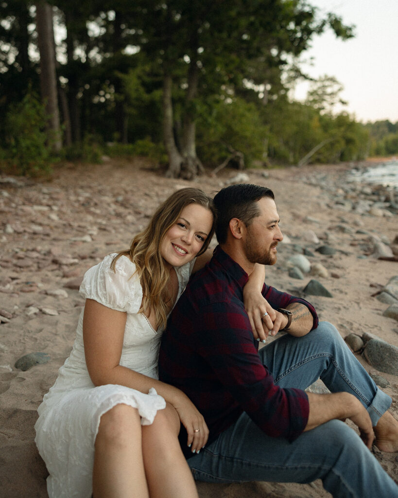 Couple sitting together on the beach during their engagement session at Little Presque Isle.