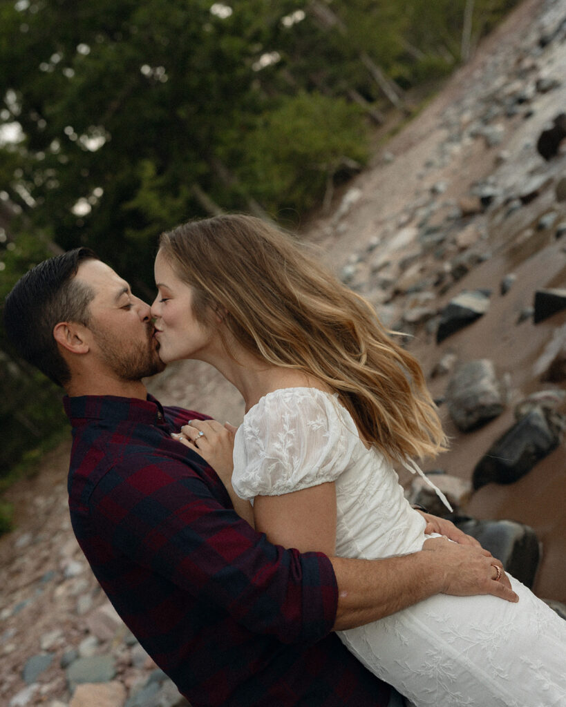 Couple kissing along the shoreline.