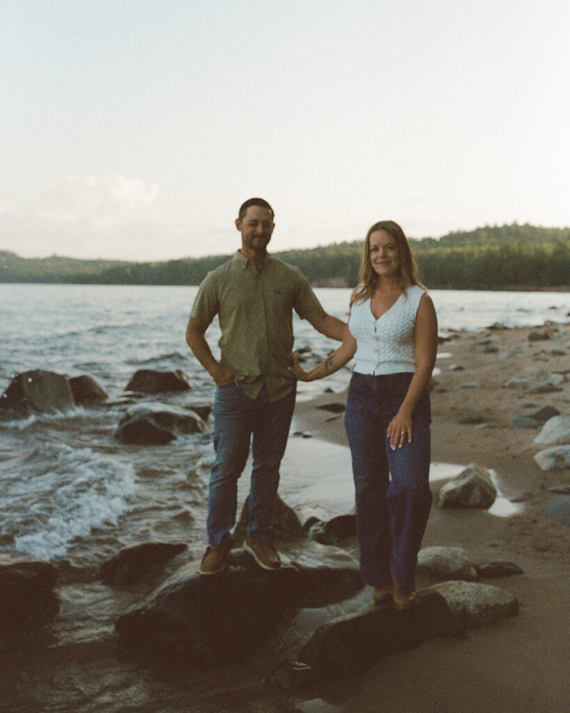 Film photo of a couple holding hands on the rocky Lake Superior shoreline at Little Presque Isle.