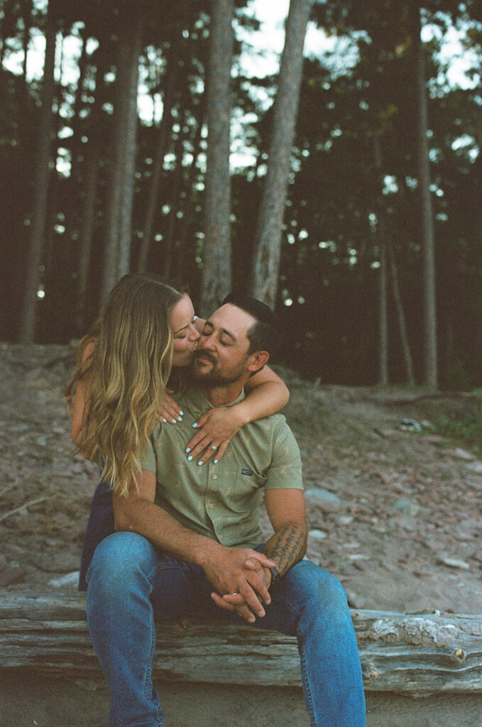 Couple kissing among the trees during their engagement session in Marquette, Michigan.