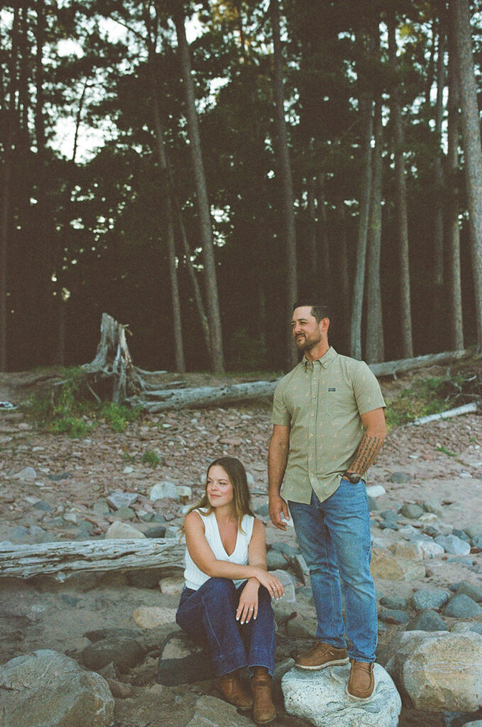 Couple posing together among the rocks and tall trees at Little Presque Isle in Marquette.