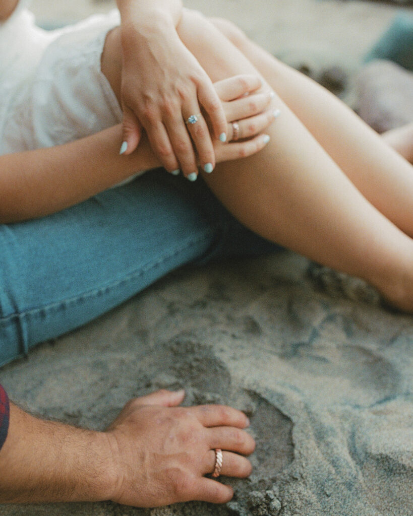 Close-up of a couple’s hands and rings resting on a rock beside Lake Superior.